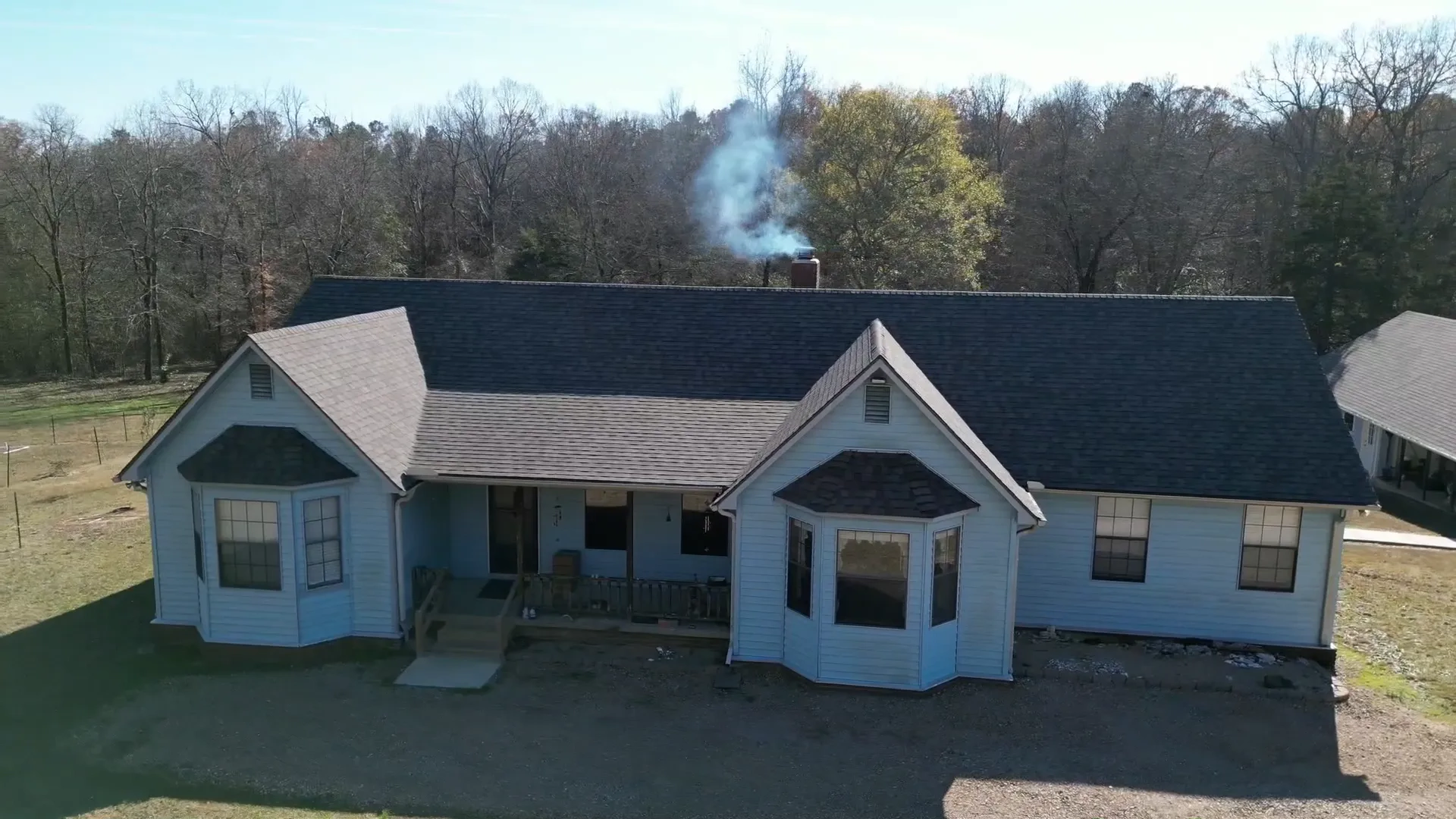 White Arkansas farmhouse finished with a new dark shingle roof on a clear winter day